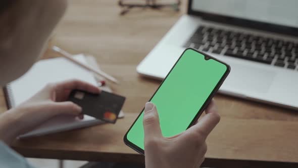 Smartphone with Green Screen for Chroma Key Compositing and a Credit Card in the Hands of a Woman