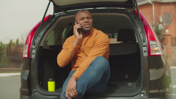 African Man Traveler in Car Trunk Speaking on Phone