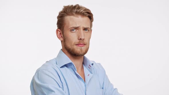 Serious Young Caucasian Male with Blue Eyes and Brown Beard Approves on White Background