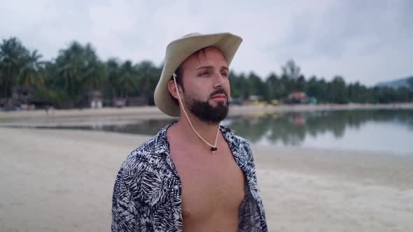 Face Closeup of Young Adult Hipster Traveler Smiling at Camera While Walking on Sandy Island Spit