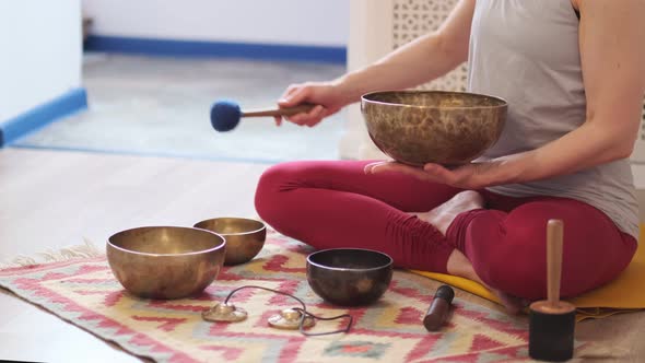 Woman Playing on Tibetan Singing Bowl While Sitting on Yoga Mat