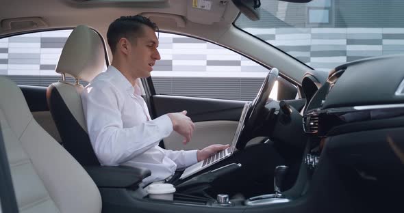 Portrait of Young Businessman Man Talking By Videoconference Using Laptop While Sitting in the Car