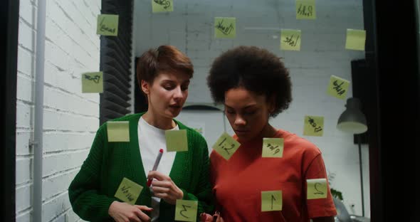 A Woman is Drawing a Business Strategy on a Glass Board Working with Assistant