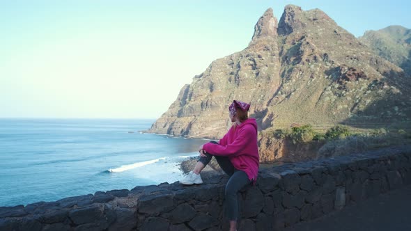 A Woman Walks Next to the Ocean Enjoying the Calm Scenery Against the Background of the Volcanic