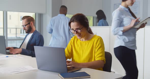 Happy Young Businesswoman Using Computer at Workplace in Modern Office