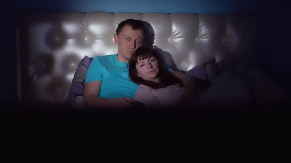 Family lying on bed at night watching tv, camera movement, rest concept