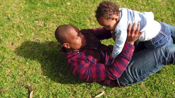 African American Bald Father Playing with Little Son on Lawn