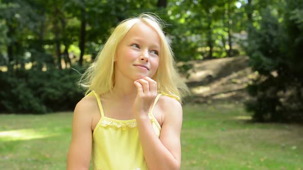 Little Happy Girl Stands in the Park and Thinks About Something - Dreamer