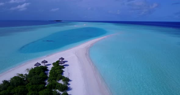 Wide angle drone tourism shot of a sandy white paradise beach and blue water background in vibrant 4