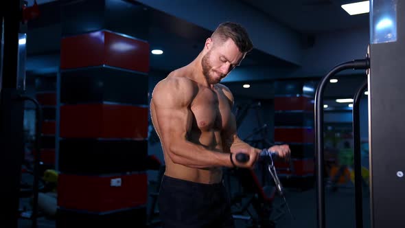 Handsome strong young bodybuilder works out on sport equipment. Strong abs.