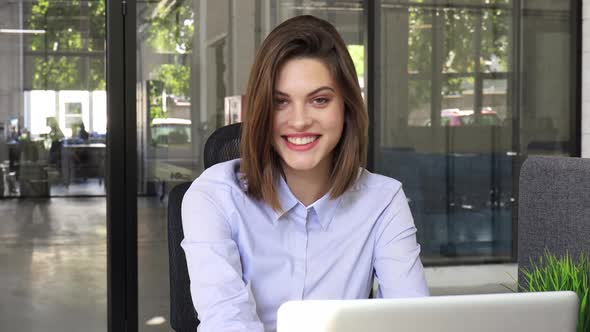Beautiful Smiling Businesswoman Worker Looking at Camera Sitting at Modern Office