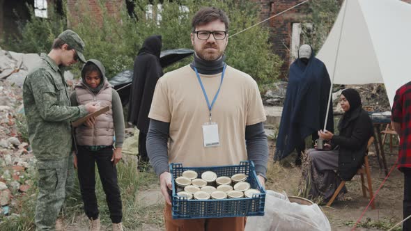 Portrait of Volunteer with Tinned Food at Refugee Camp