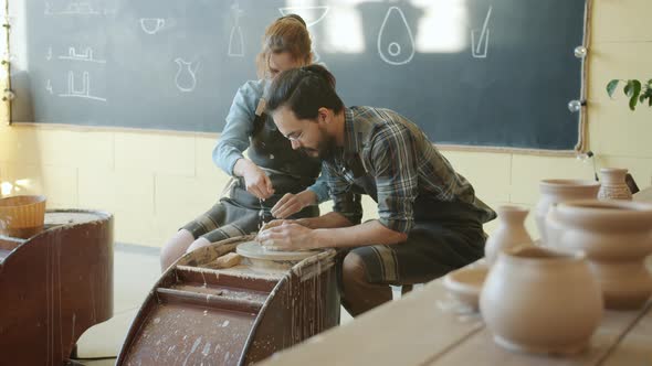 Slow Motion of Man and Woman Making Pot of Spinning Wheel in Pottery Workshop