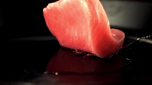 Super Slow Motion Raw Tuna Steak Falls on a Pan with a Splash of Oil