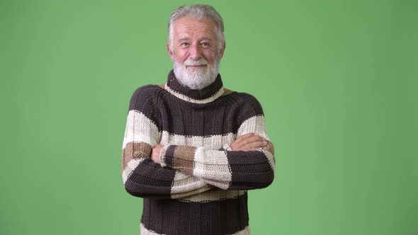 Handsome Senior Bearded Man Wearing Warm Clothing Against Green Background