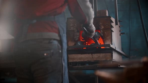 Blacksmith Workshop  a Man Puts Metal Thing in the Oven Using Pincers