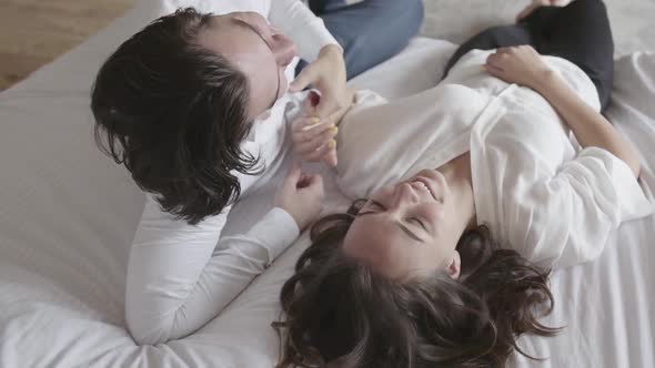 Overhead Shot Happy Young Couple Lying on the Bed Talking Close-up. Top View Relaxing Man and Woman