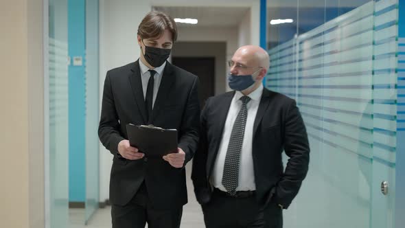 Medium Shot of Two Confident Businessmen in Covid19 Face Masks Walking in Office Hallway Talking