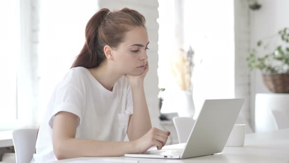 Pensive Young Woman Thinking and Working on Laptop