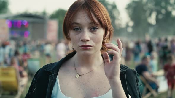 Portrait of ginger haired young caucasian woman at music festival showing neutral emotions. Shot wit