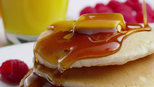 Pouring syrup onto pancakes, closeup