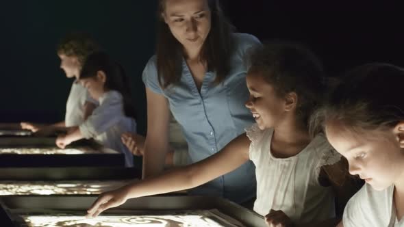 Art Teacher Talking to Girl in Sand Animation Class