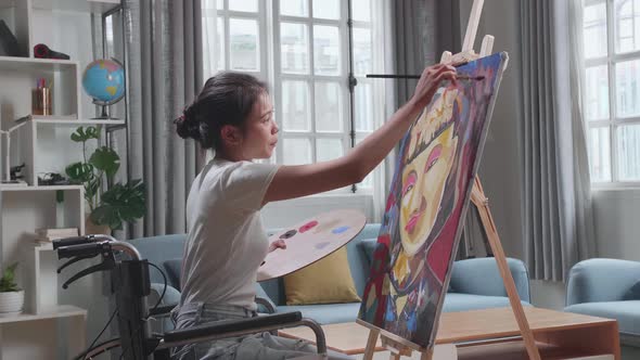 Talented Female Artist Sitting On Wheelchair Using Paint Brush She Creates With Oil Painting