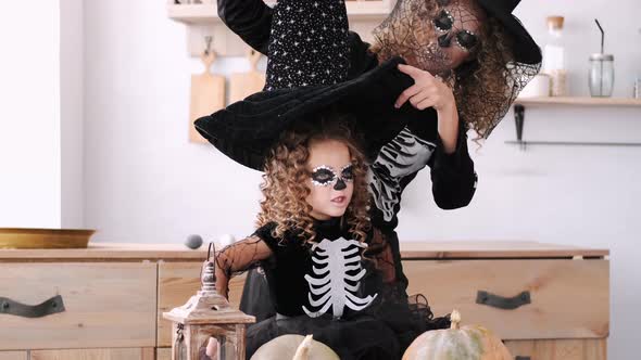 Mother and Daughter in Halloween Costumes Playing Together in Kitchen