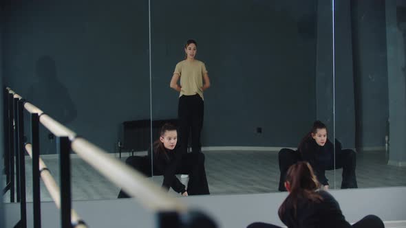 Little Girl Twins Synchronously on Dance Practice in the Studio and Their Coach Looking After Them