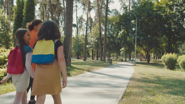 School Kids with Backpacks Following Young Female Teacher Outdoors