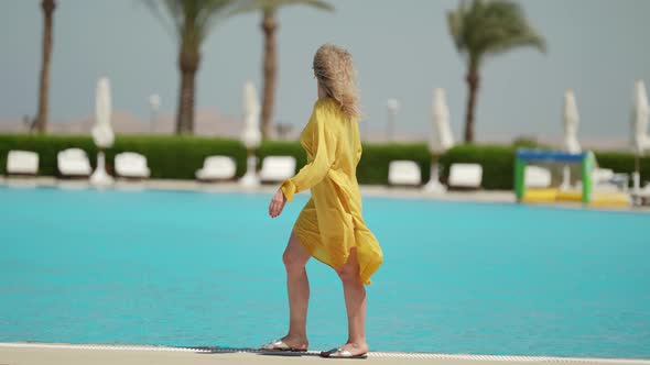 Rest in Luxury Hotel Woman is Strolling Along Open Pool in Sunny Day