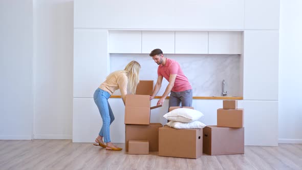 Young woman blonde with long loose hair and bearded husband open cardboard box