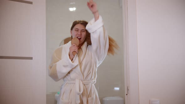 A Young Woman Dancing and Singing in a Hair Brush Wearing a Bathrobe