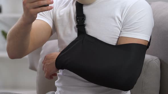 Angry Man in Cervical Collar and Arm Sling Typing on Phone, Insurance Problem