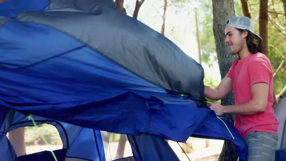 Happy man setting up tent in park 4k