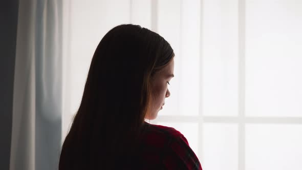 Silhouette of Woman Standing By Window in Room Backside View