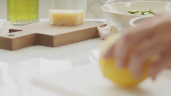 Crop woman cutting fresh lemon on chopping board