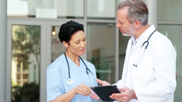 Two doctors discussing over digital tablet