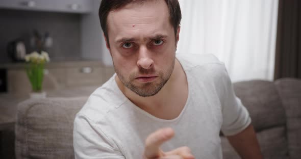 Piercing Serious Menacing Look at Camera Young Depressed Man Sitting on Sofa Frustrated Showing