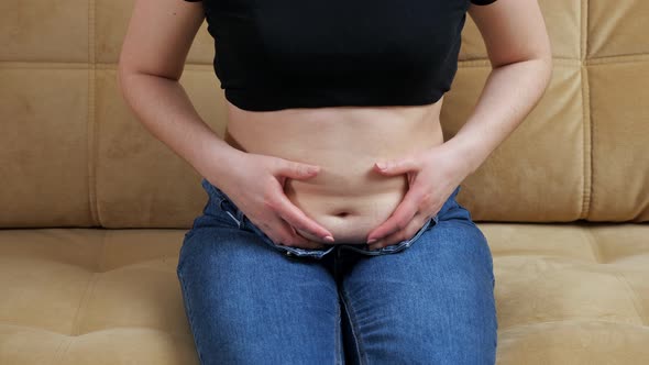 Unrecognizable Woman Touching Belly Fat While Sitting on the Couch