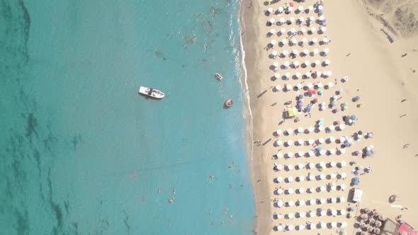 Top View of Sand Beach with Umbrellas Boat and Swimming People in Sea Bay Water
