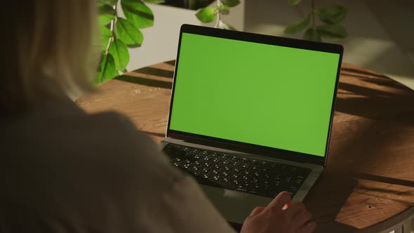 Handheld Shot of a Woman Watching Laptop Computer with Green Screen Chroma Key Indoors