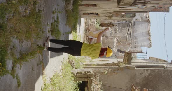 Vertical video of a girl engineer or archaeologist looking at the city destroyed by the earthquake