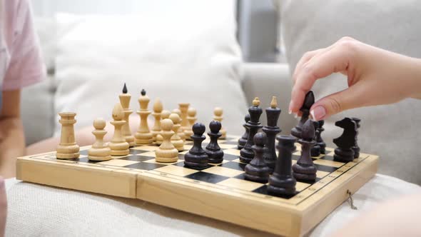 Mother and Daughter Playing Chess and Sitting on a Sofa in Living Room