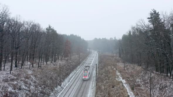 Passenger train passing through winter forest. 