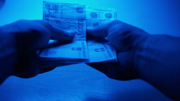 Man Counts Money in Rubles in His Hands Illuminated By Police Flasher