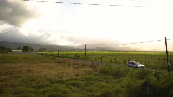 Car driving on a countryside road near a tropical volcano.