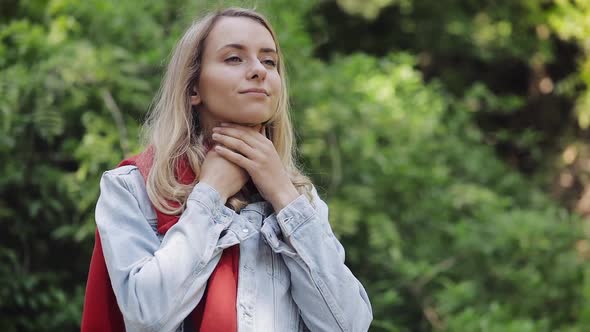 Sick Young Woman Wearing Red Scarf Feeling Bad Suffering From Throat Pain, Standing in the Park