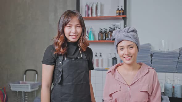 Portrait of Asian hairdresser give treatment service to young girl customer on washing bed in salon.
