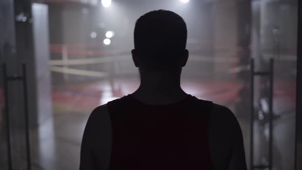 Back View of Confident Sportsman Stretching Neck and Walking To Boxing Ring. Camera Follows